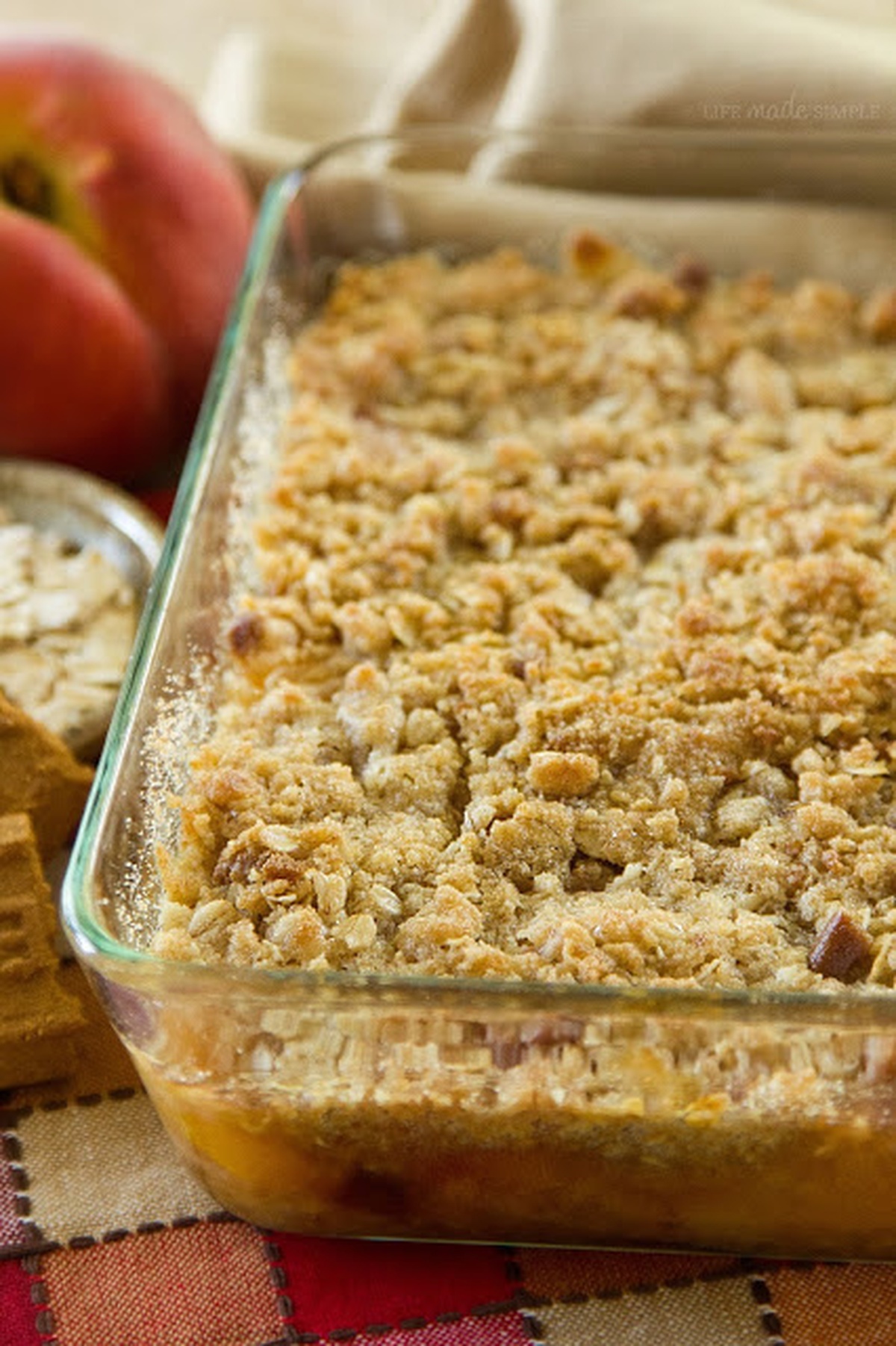 A freshly baked Biscoff Peach Crisp with a golden crumble topping in a glass baking dish.
