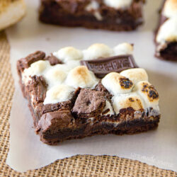 Close-up of a baked chocolate s’mores cookie bars on parchment paper.