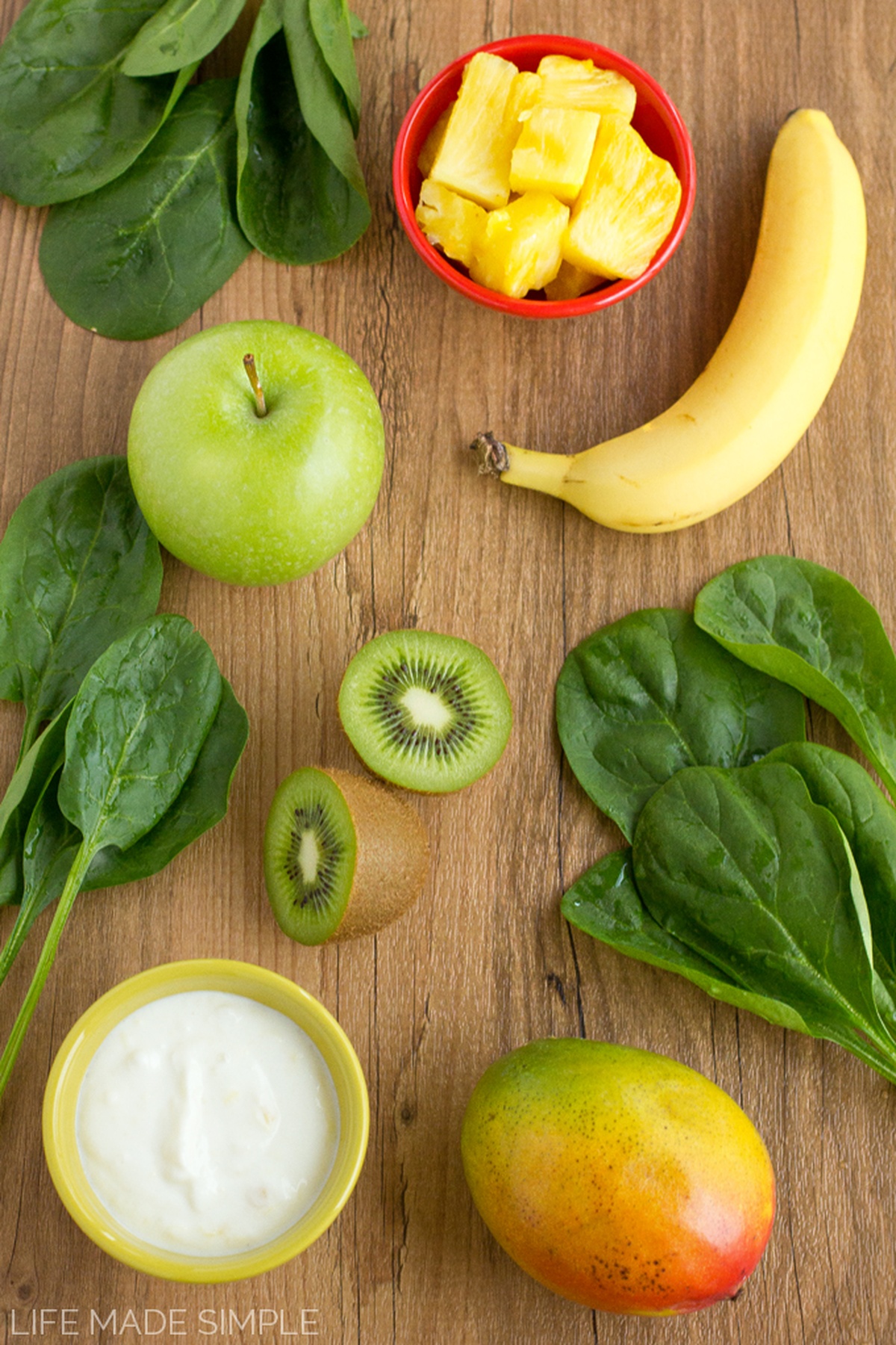 Ingredients for a green monster juice arranged on a wooden surface.