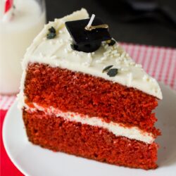 A close-up of a slice of red velvet cake with vanilla bean cream cheese icing.