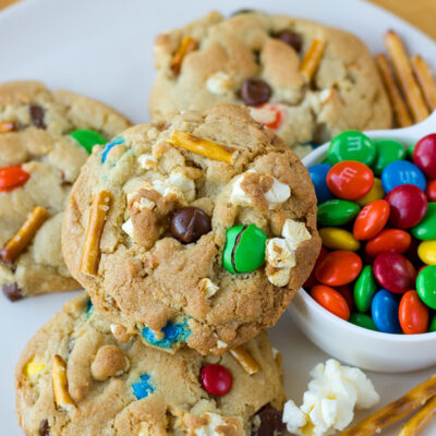 A plate of movie theater cookies, alongside a bowl of colorful M&Ms and pretzel sticks.