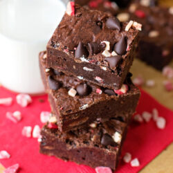 A stack of easy peppermint brownies placed on a red napkin with a glass of milk.