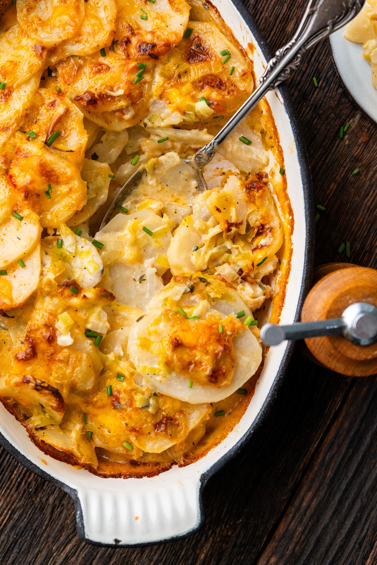 Spoon getting a serving of gratin from a dish of leek and potato gratin.