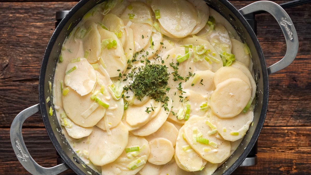 Potatoes and thyme added into the skillet to cook.