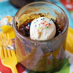 One minute mug cake topped with vanilla ice cream and rainbow sprinkles.