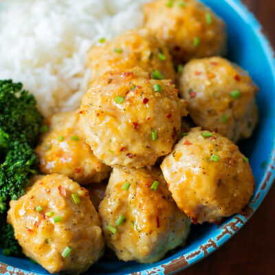 A blue bowl filled with orange chicken meatballs.