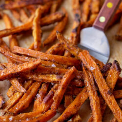 Close-up of crispy baked sweet potato fries with a spatula.