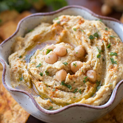 Garlic hummus in a bowl, topped with chickpeas, paprika, and olive oil.