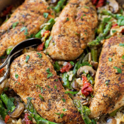 A top-down view of Tuscan skillet chicken with asparagus, mushrooms, and rice.