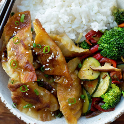 Beef gyoza served with rice and stir-fried vegetables in a bowl.