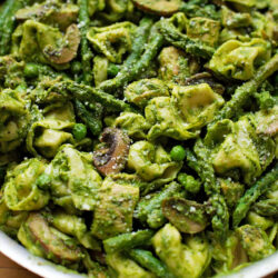 Pesto tortellini with chicken in a skillet.