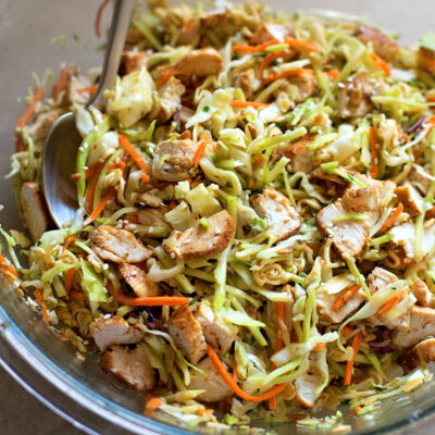 Asian coleslaw with ramen in a glass mixing bowl.