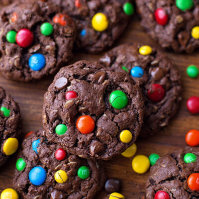 Chocolate peanut butter monster cookies on a wooden surface.
