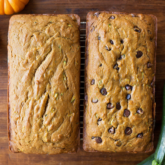 two uncut bread loaves on a cooling rack, one with chocolate chips