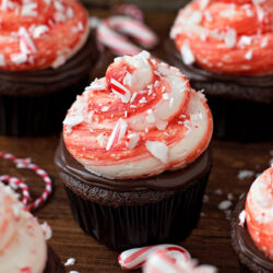 Chocolate cupcake with peppermint frosting and crushed candy cane on a wooden surface.