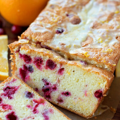 Sliced cranberry orange cake on a wooden surface.