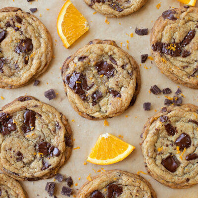 Freshly baked Orange Dark Chocolate Chunk Cookies on a parchment-lined baking sheet.