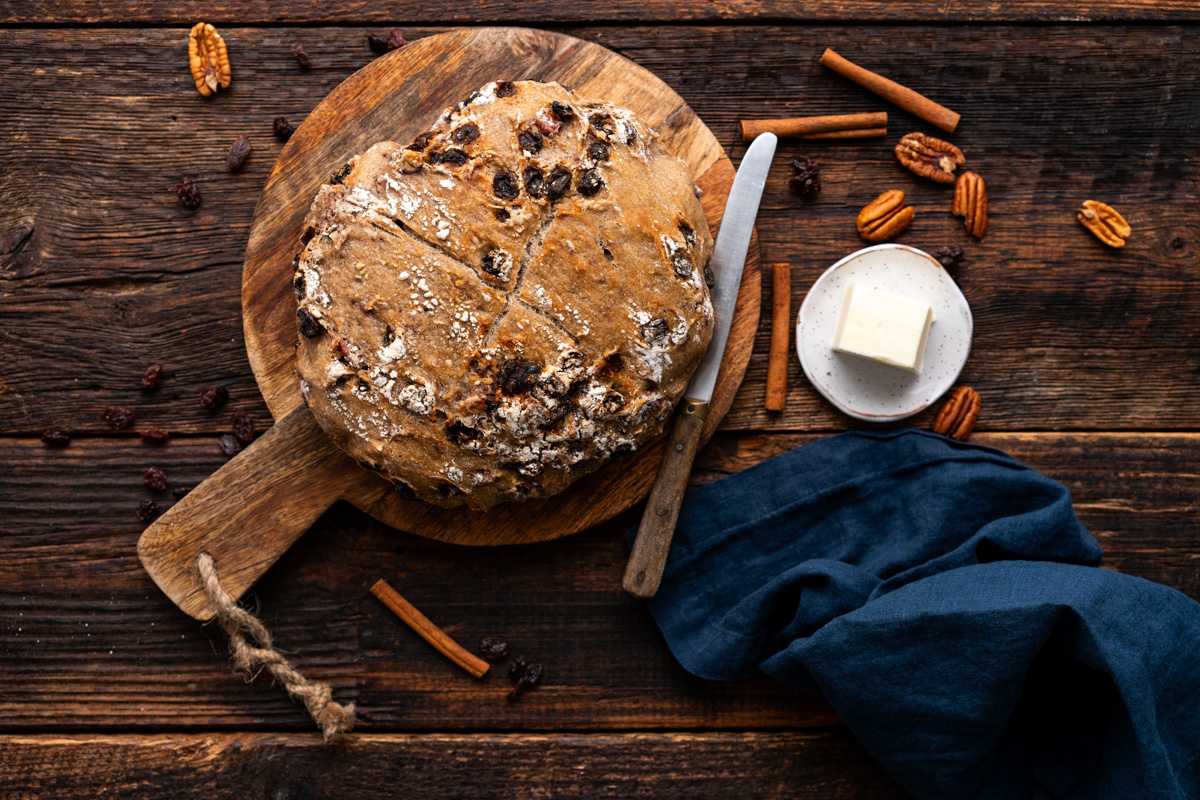 Loaf of pecan raisin bread sitting on a cutting board.