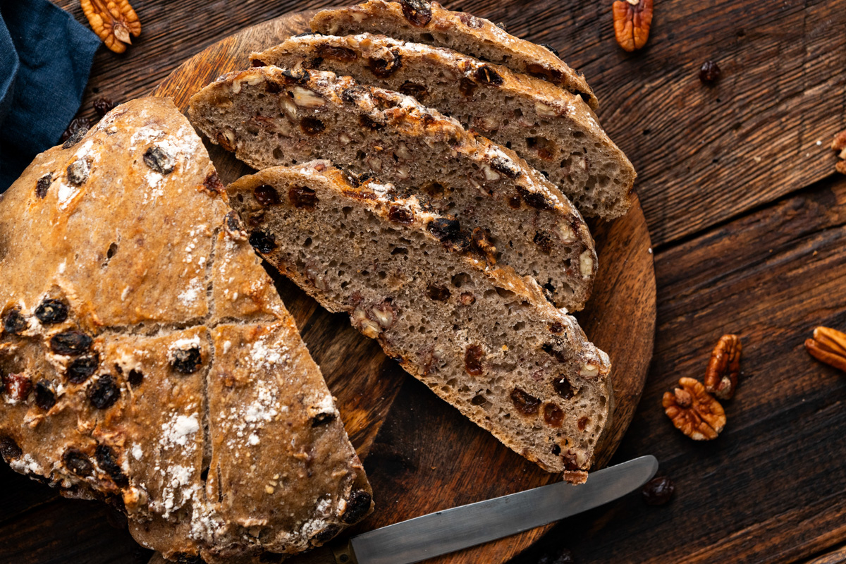 Loaf and slices sitting on a cutting board.