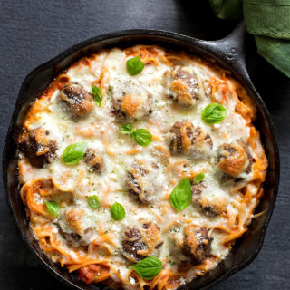 Baked spaghetti and meatball in a skillet garnished with fresh basil. | lifemadesimplebakes.com
