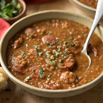 A bowl of smoked sausage and lentil soup.