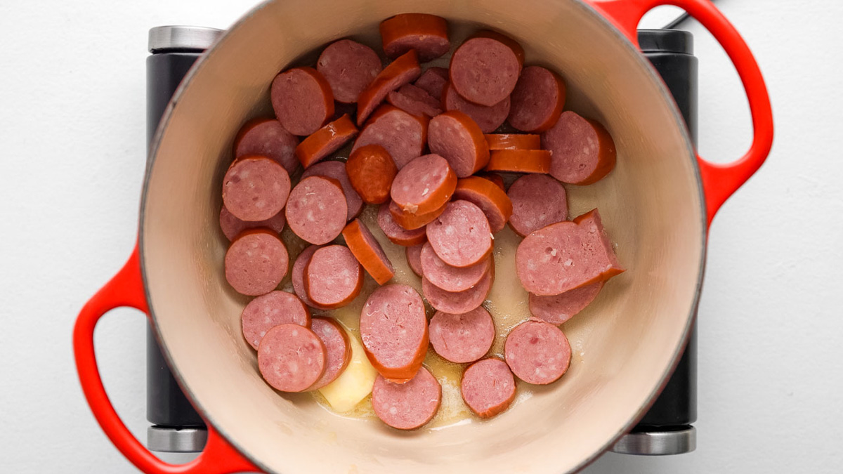 Sausage cooking in a Dutch oven.