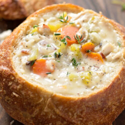 A crusty bread bowl with chicken and wild rice soup.