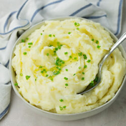 A bowl with mashed potatoes garnished with chives.