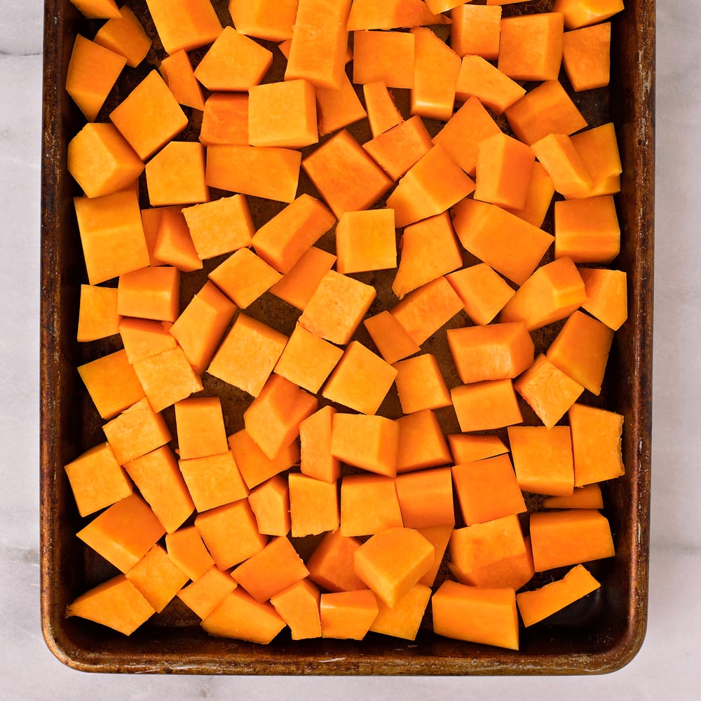Sweet and savory maple roasted butternut squash has become a staple side dish for dinner ands holidays. It's flavorful, simple and beyond delicious! Butternut squash cubes on baking sheet