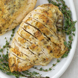 Sliced, bone-in chicken breast placed on a white platter.