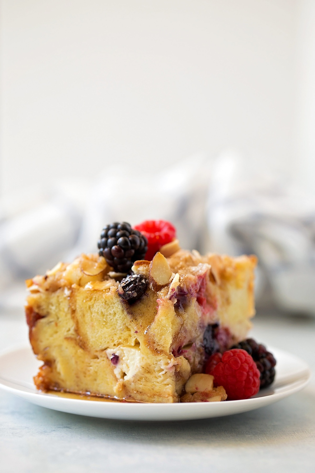 A slice of mixed berry French toast casserole on a white plate.