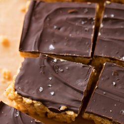 Sliced chocolate peanut butter rice Krispie squares topped with sea salt, arranged on parchment paper.