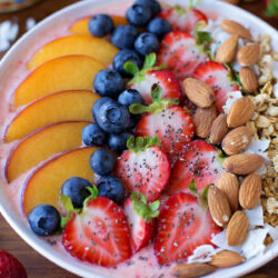 Fruit smoothie bowl with fresh fruit and almond toppings.