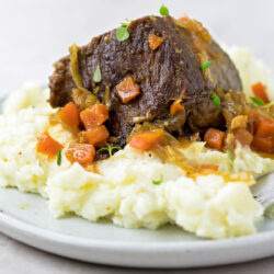 A plate with Instant Pot short beef ribs served on mashed potatoes.
