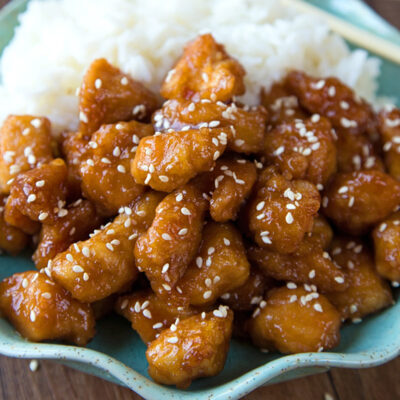 Better than takeout chicken served on a plate with white rice.