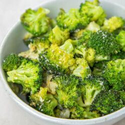A close-up of oven roasted broccoli in a serving bowl.