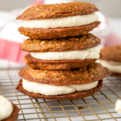 Homemade oatmeal cream pies stacked on a wire rack.
