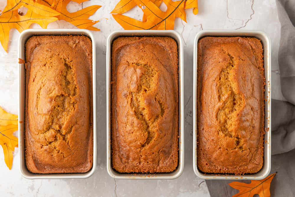 This crumbly & delicious pumpkin bread is the perfect cozy fall treat! Warmly spiced with & nutmeg cinnamon, it's delish and easy to make. Three loaves of pumpkin bread in loaf pans
