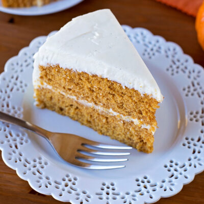 A slice of pumpkin layer cake on a white plate.