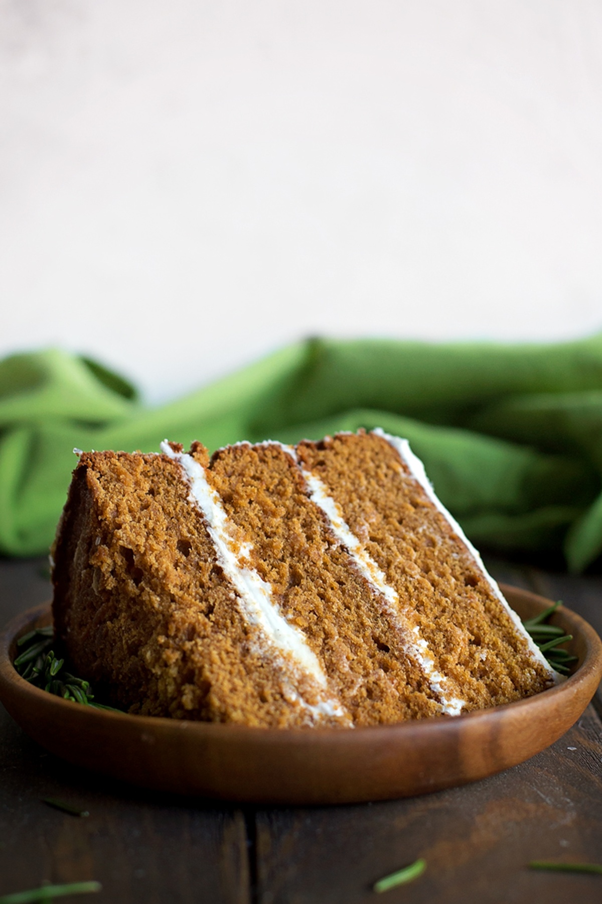 A single slice of gingerbread cake on a wooden plate.