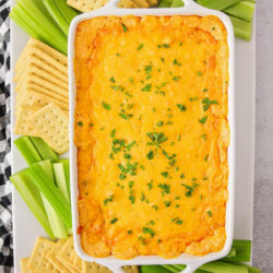 Baked buffalo chicken dip served in a baking dish with celery and crackers.