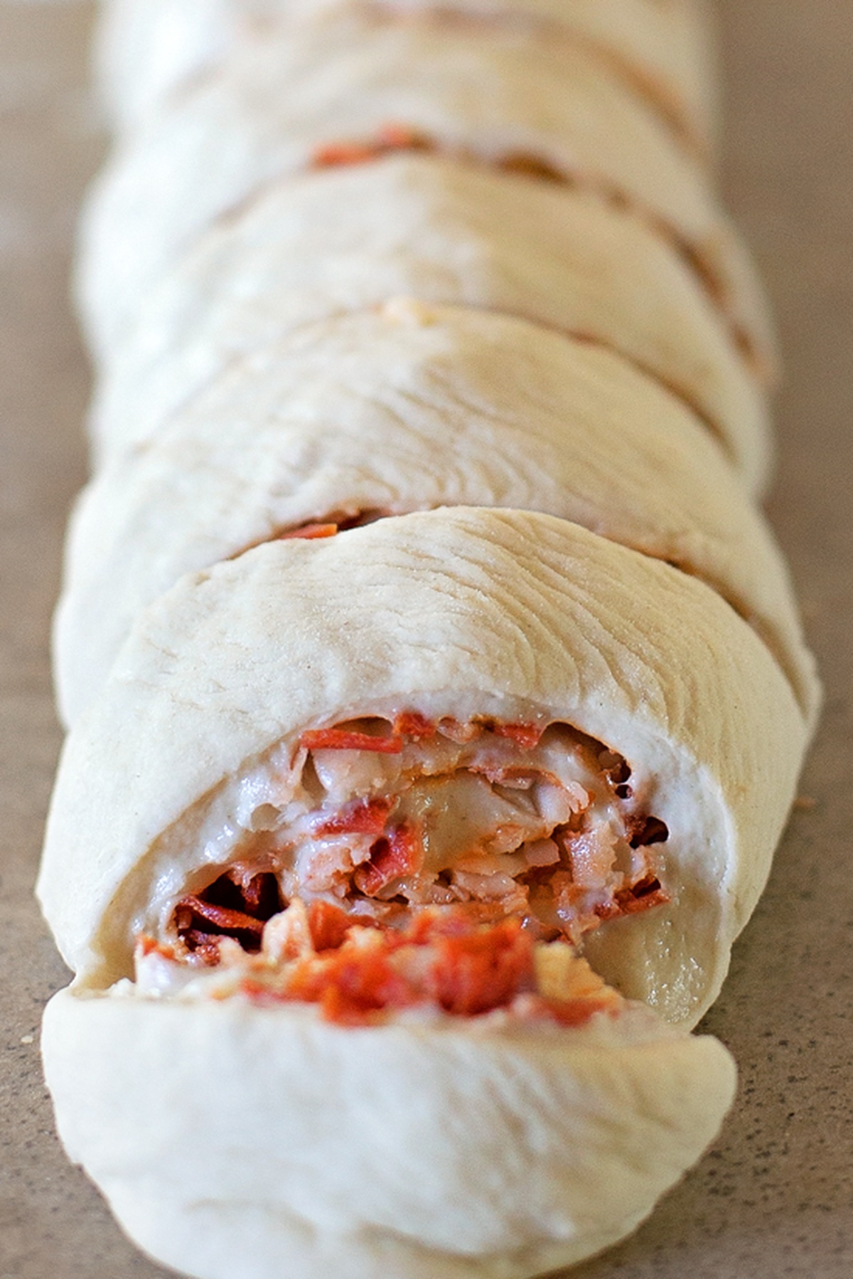These individual pepperoni pizza pinwheels are fun to make and eat! They're stuffed full of gooey mozzarella cheese and lots of crispy pepperoni. Unbaked rolled pizza dough sliced into even pinwheels.