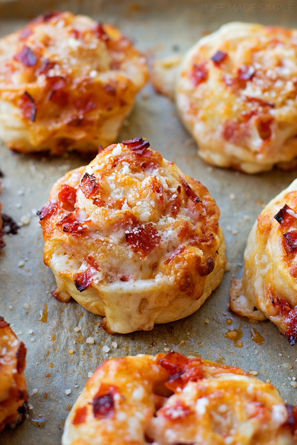 These individual pepperoni pizza pinwheels are fun to make and eat! They're stuffed full of gooey mozzarella cheese and lots of crispy pepperoni. Golden-brown baked pepperoni pinwheels on parchment paper.