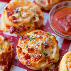 Pepperoni pinwheels arranged on red and white parchment paper.