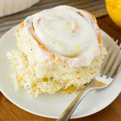 A single lemon poppy seed sweet roll on a white plate.