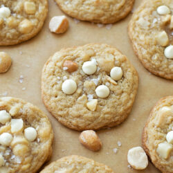 Macadamia nut cookies with white chocolate resting on a parchment paper.