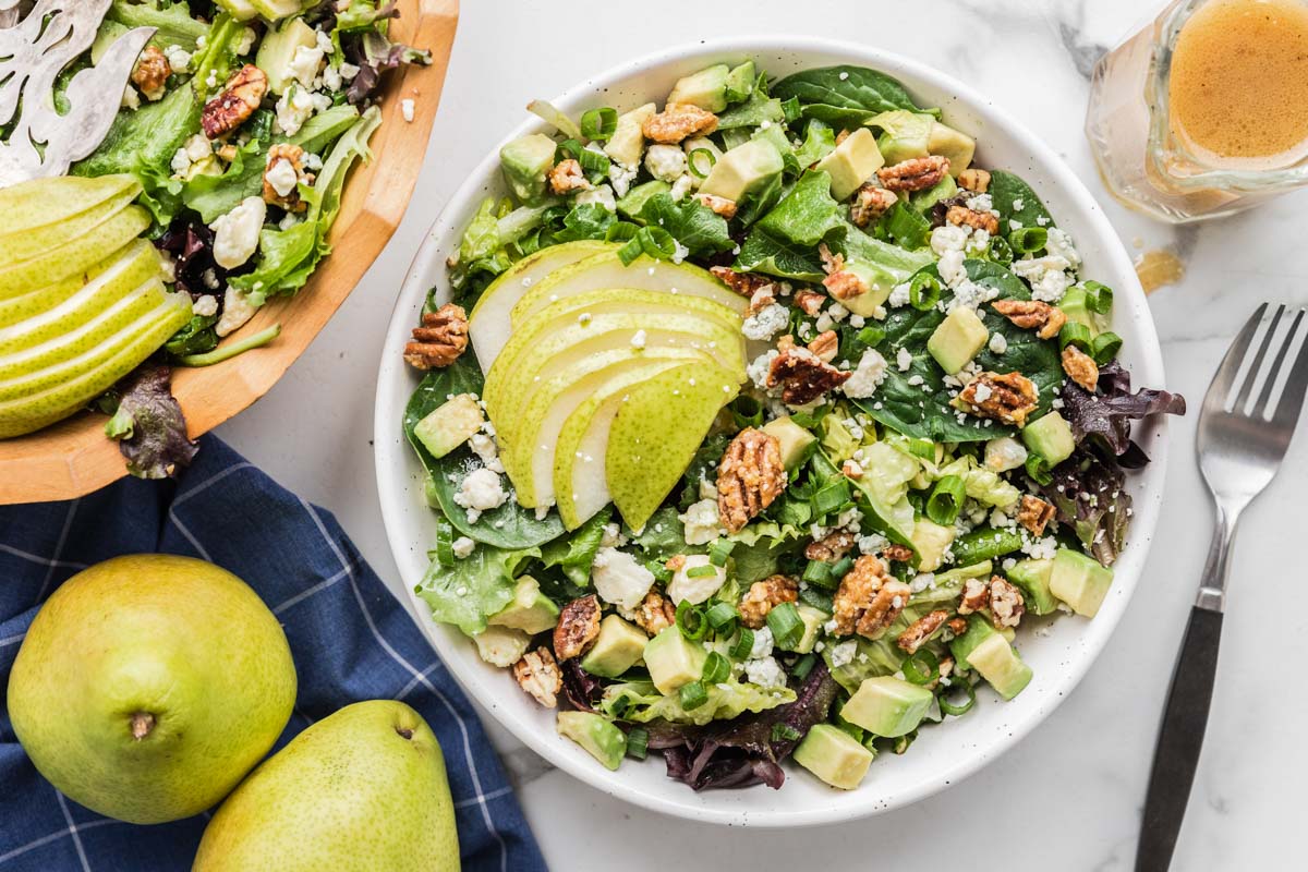 Pear salad topped with fresh pear slices in a white bowl