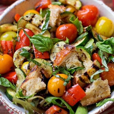 Greek panzanella salad with dressing for panzanella salad in a serving bowl.