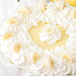Banana custard pie topped with whipped cream swirls and banana slices.