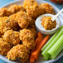 Plate of crispy Buffalo chicken nuggets with celery and carrot sticks.